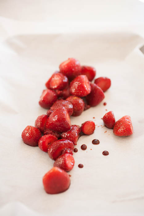 frozen strawberries on parchment paper with balsamic vinegar