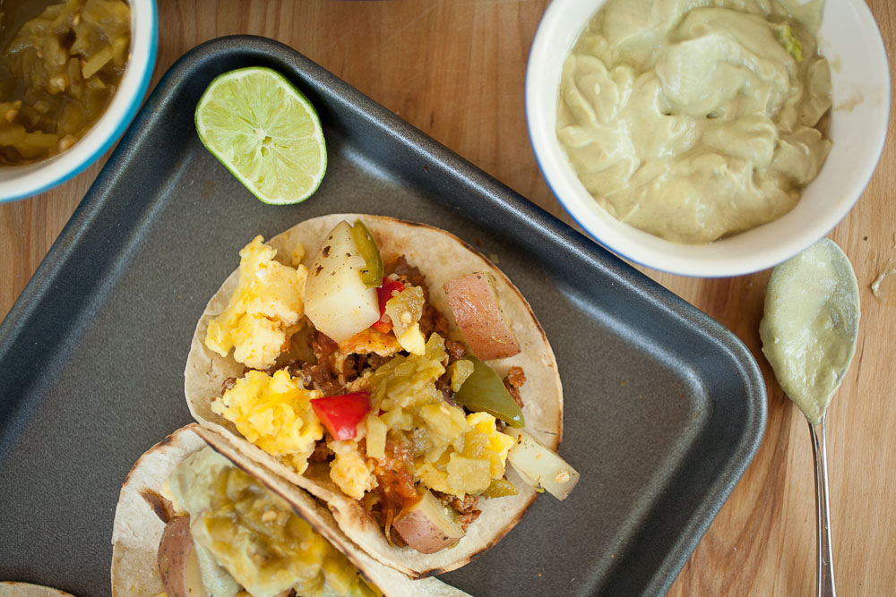 breakfast tacos with eggs, lime, and avocado cream on a sheet pan