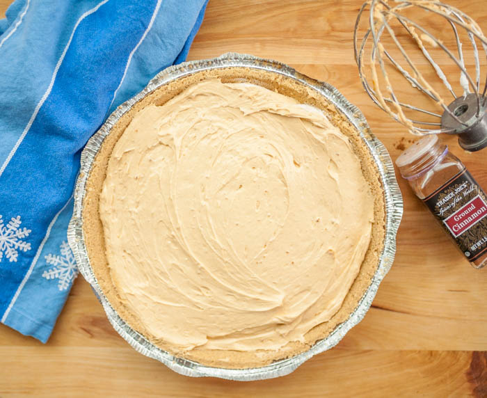 An easy to make no-bake pumpkin cheesecake on a cutting board with a wire whisk