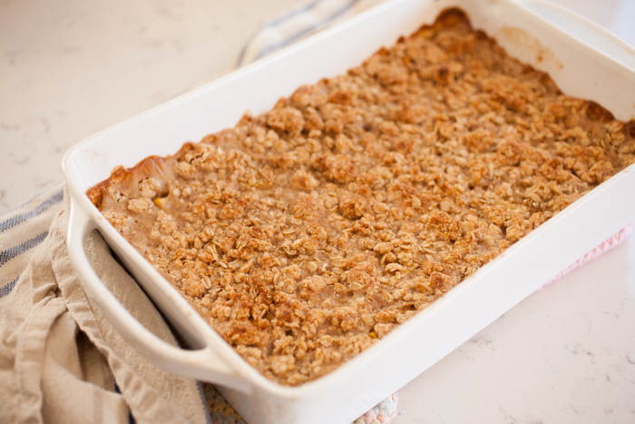 oatmeal with crisp topping in a white baking dish with a dish cloth 
