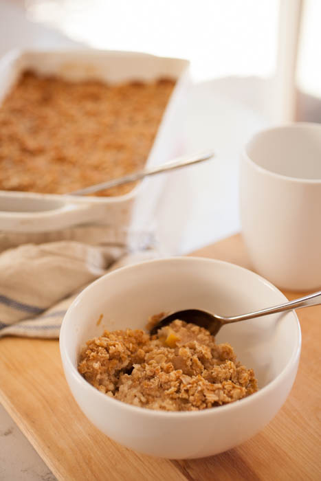 bowl of oatmeal crisp with coffee and oatmeal in baking dish behind.