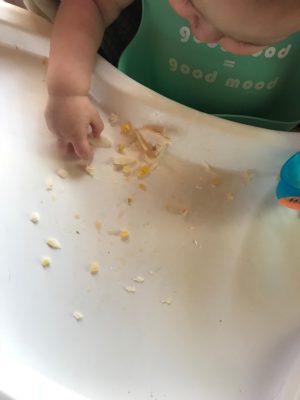Baby hand with white fish and corn 