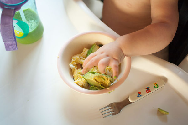 baby hand with a bowl of egg bites and avocado